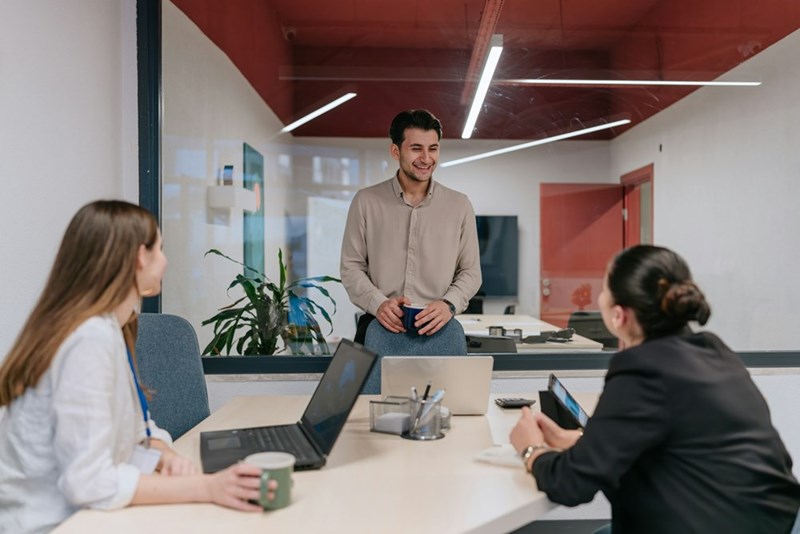Young professionals collaborating during a modern office meeting in a glass conference room.