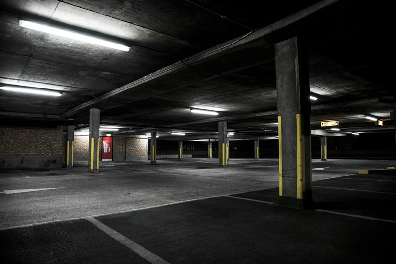 Empty underground parking garage with concrete pillars and dim industrial lighting.