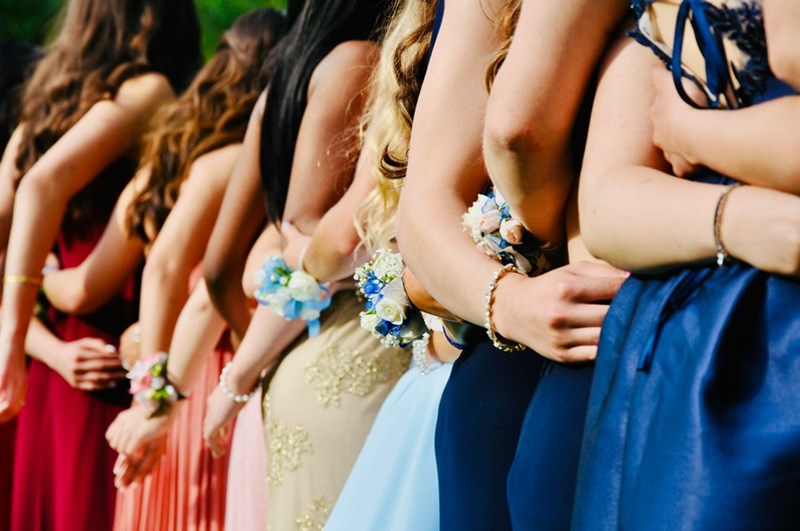 A group of teenagers dressed in gowns pose for a photo before the prom dance