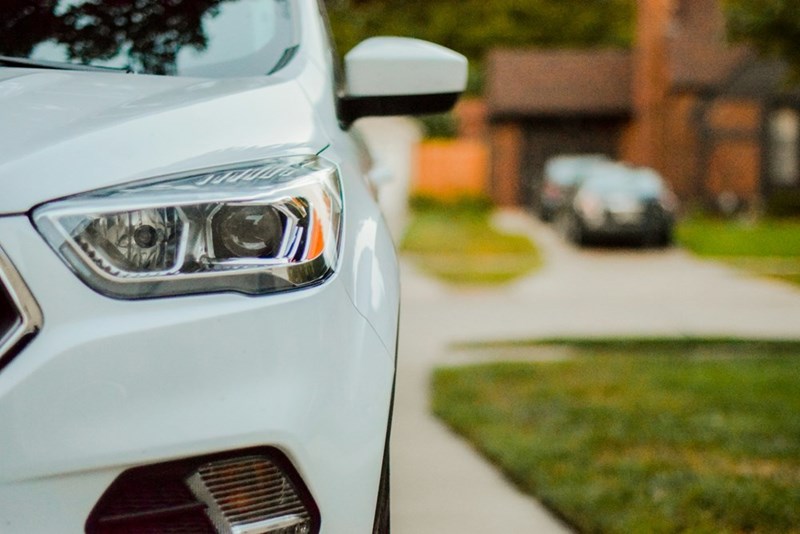 White SUV parked near residential homes in a suburban neighborhood street.