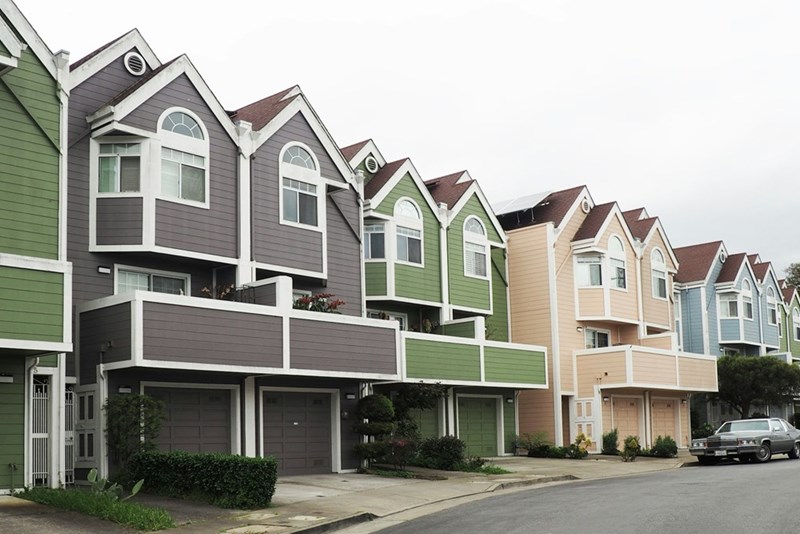 Colorful row of modern townhouses with attached garages in residential neighborhood.