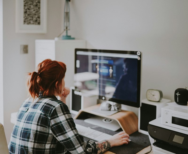 A woman remote works at a desk at home