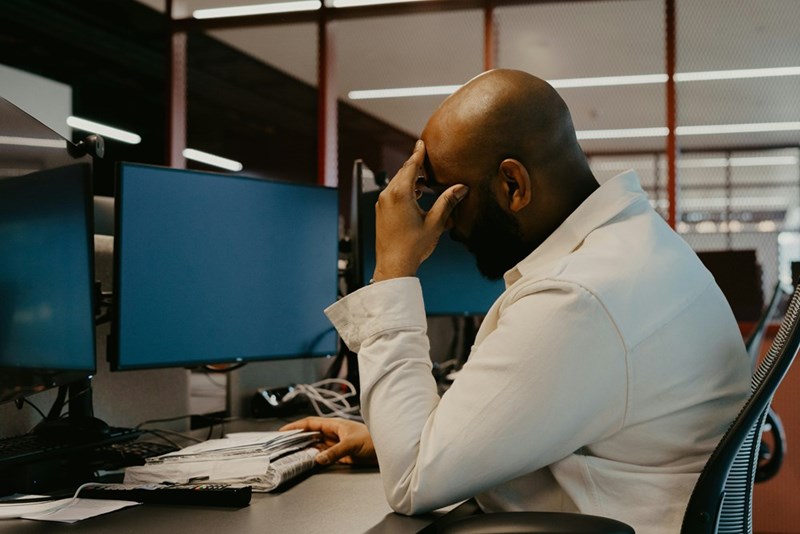 A man sitting at a desk with his head in his hands