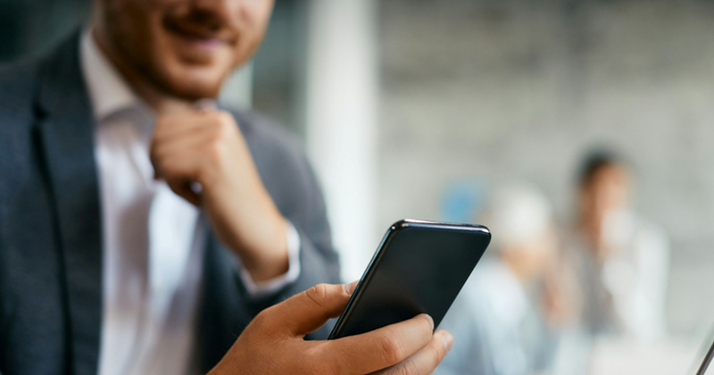 A man in a suit texts on a smartphone