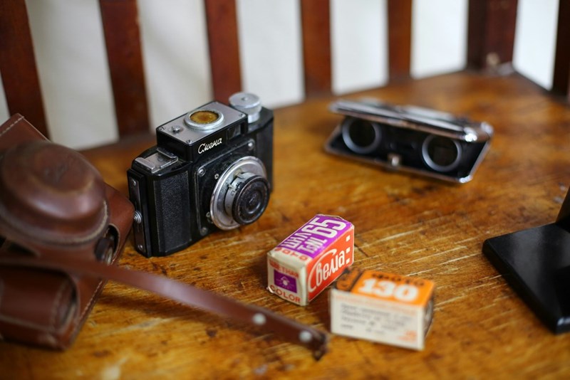 A vintage camera placed in a wood table with film by its side.