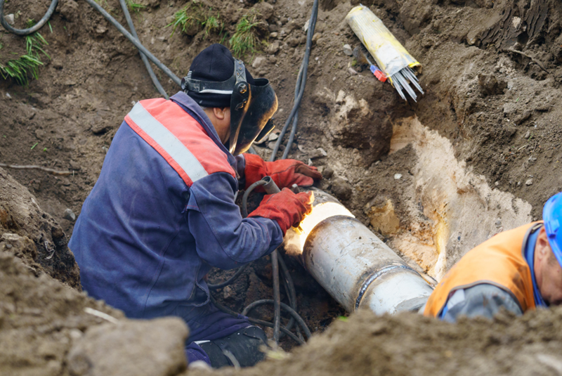 Plumber working on an outside drain pipe with full gear.