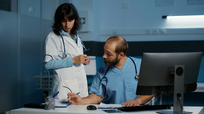 Two hospital employees review paperwork together at a workstation
