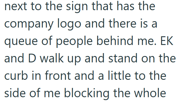 next to the sign that has the company logo and there is a queue of people behind me. EK and D walk up and stand on the curb in front and a little to the side of me blocking the whole