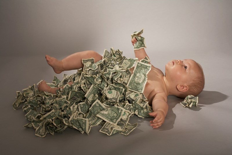 A baby laying on its back on a pile of money
