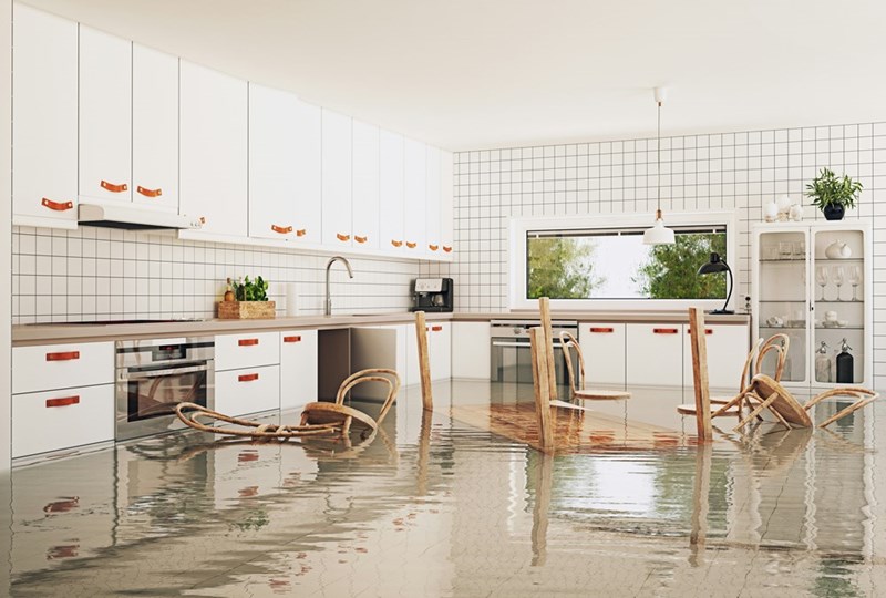 An image depicting a flooded modern kitchen with chairs floating on the water.
