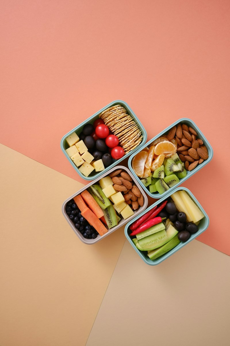 Photo of office lunches, including fruits, veggies, crackers, and other little snacks in silver tins.