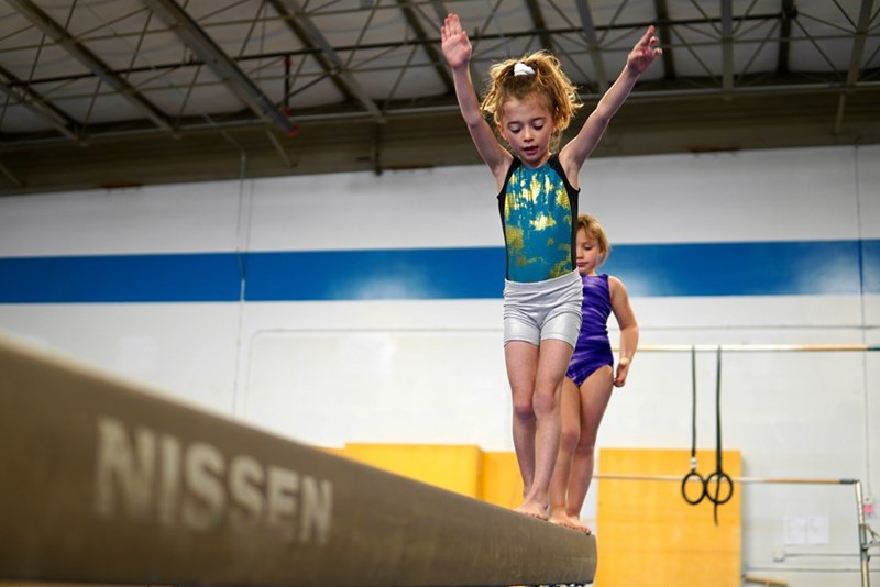A person jumping on a trampoline with a child in the background