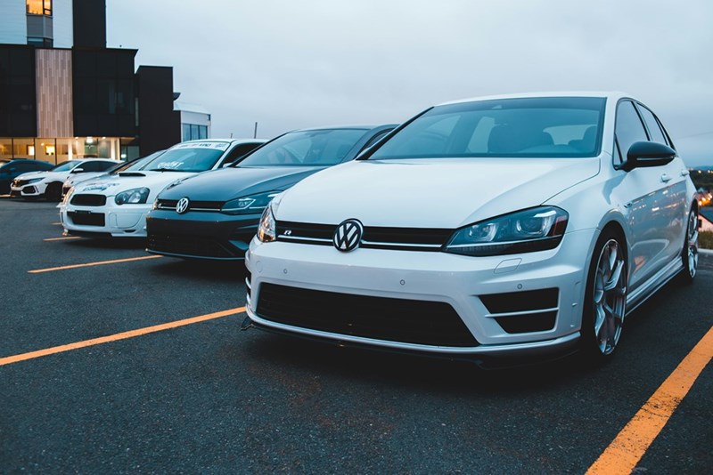 Two cars parked between each other in a public parking lot.