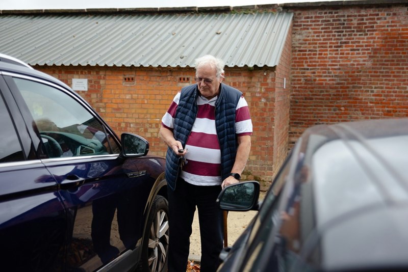Old man getting out of his black car.