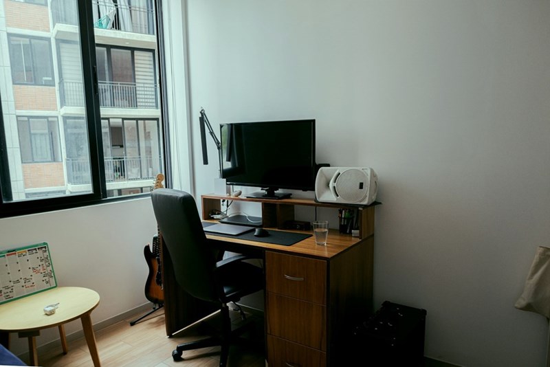 A desk, monitor, and office chair appear inside a small apartment in this illustrative remote work boundaries image