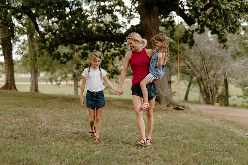 Depiction of a mother and her two children spending time outdoors together.