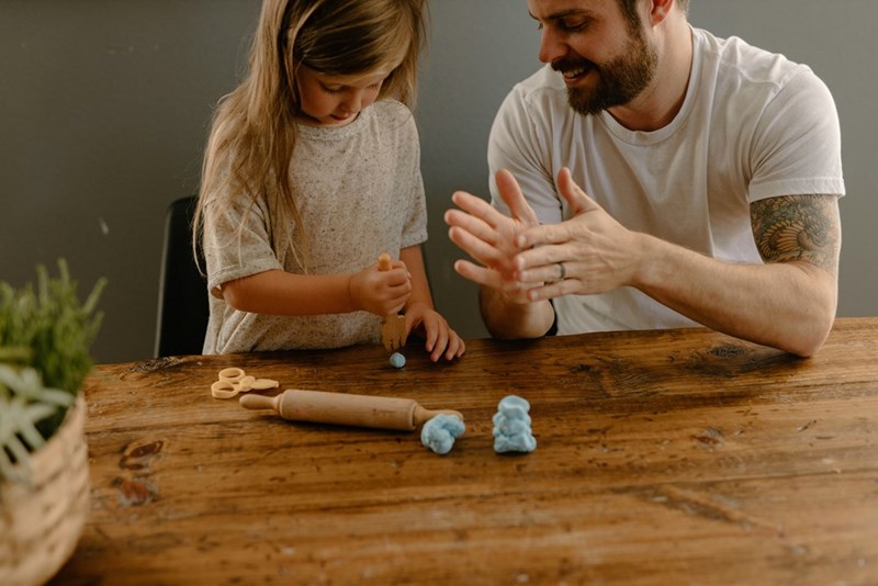 A father and daughter working on an art project together.