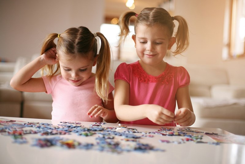 A representation of two little girls putting a jigsaw puzzle together when they're at their mom's house.