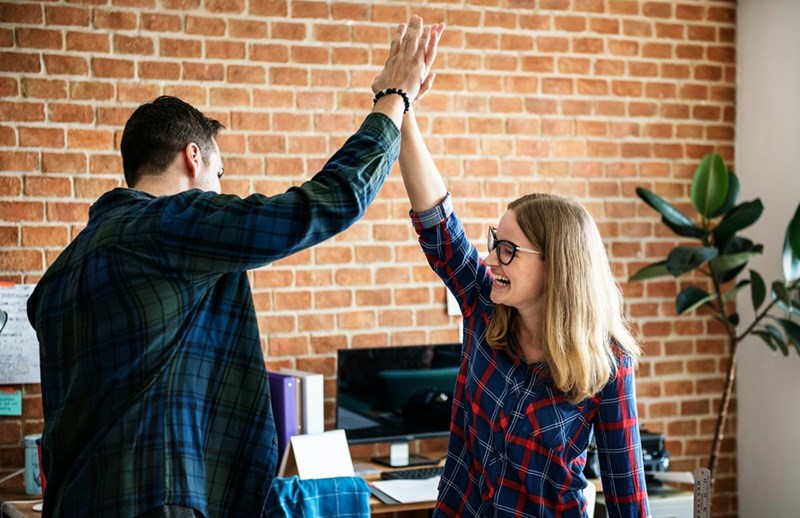 Depiction of coworkes high-fiving each other as one of them plans to quit.