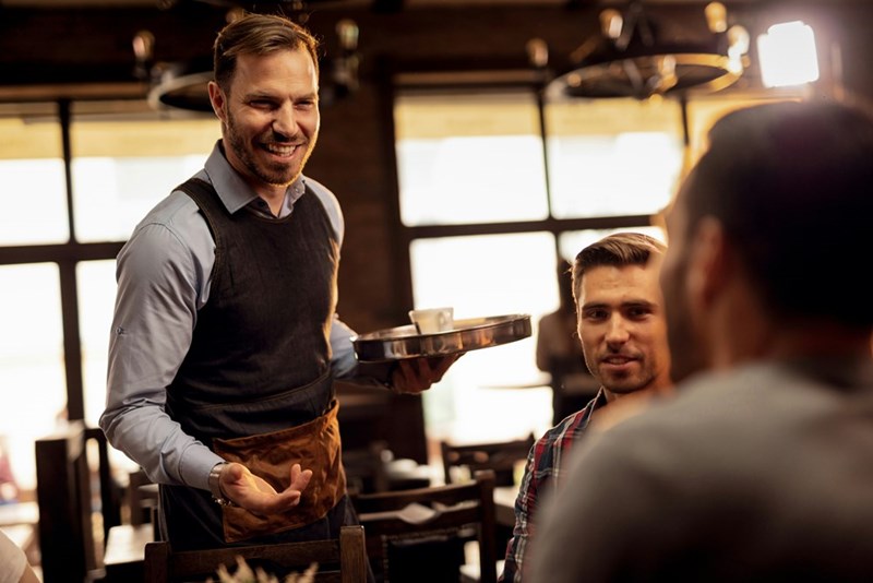 A picture of a waiter, who can afford to pay his bills because he works full-time, unlike the lazy guy in this story