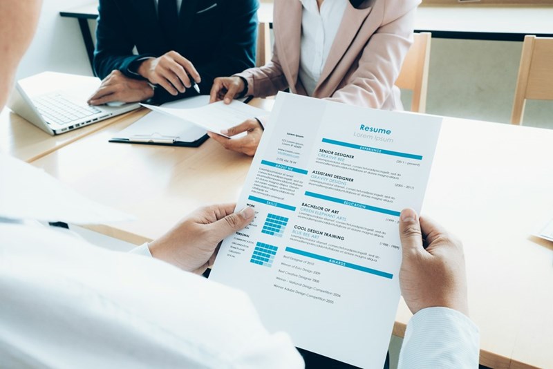 A subject dressed as a corporate recruiter reads a resume.