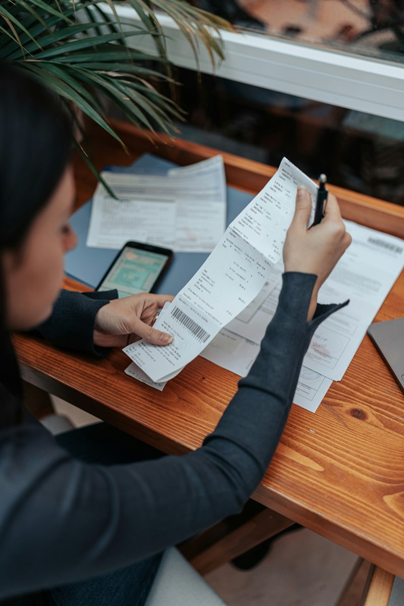 A representation of a woman calculating rent and apartment expenses while reviewing household finances.