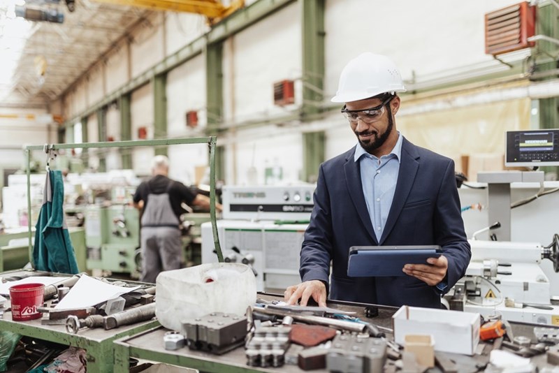 A depiction of a manufacturing manager assessing mechanical work in a warehouse.