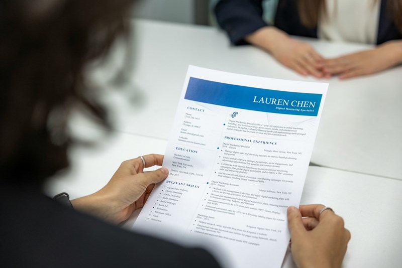 A candidate holds a resume during a job interview in this illustrative image about modern hiring practices