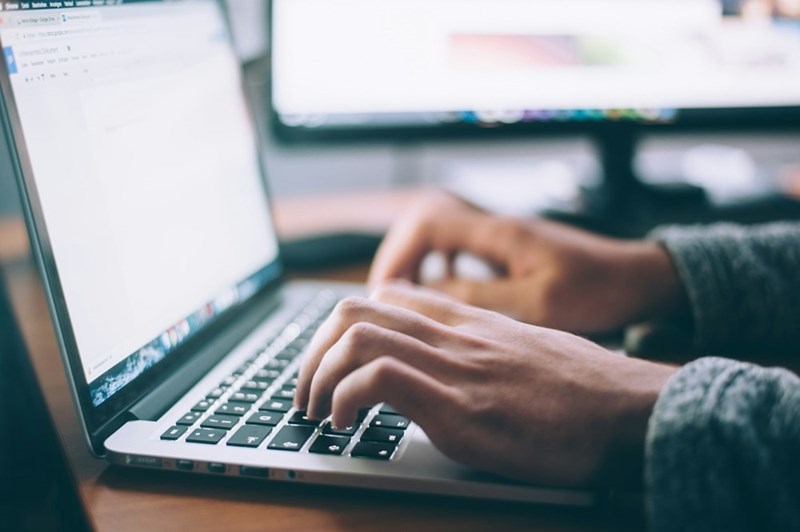 A person types on a laptop in this illustrative image about job searching and suspicious hiring practices