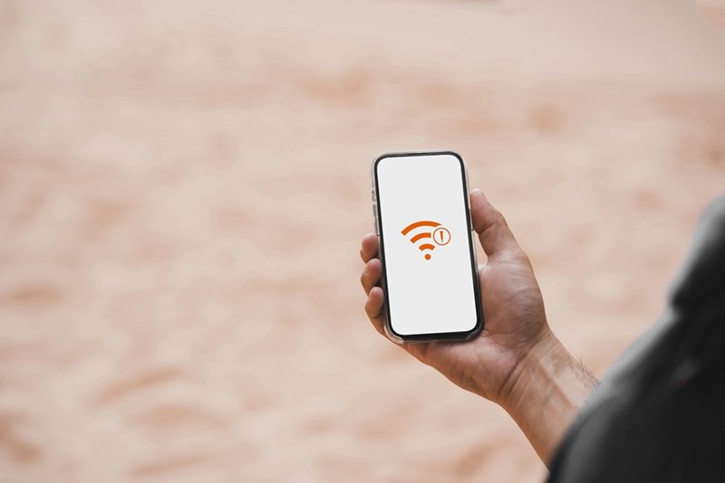 A person holding a cellphone that alerts them that there is no wifi, model.
