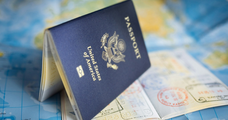 A representation of a US passport placed on another open passport and a map