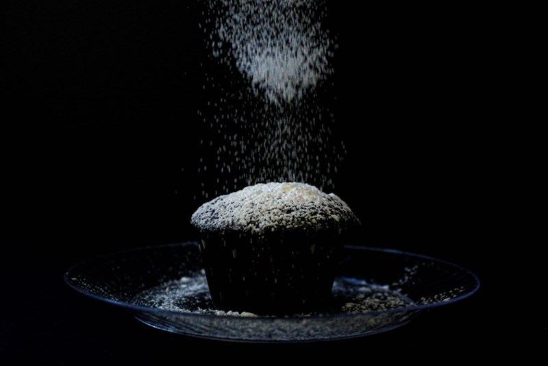 A cupcake is sprinkled with sugar on a plate
