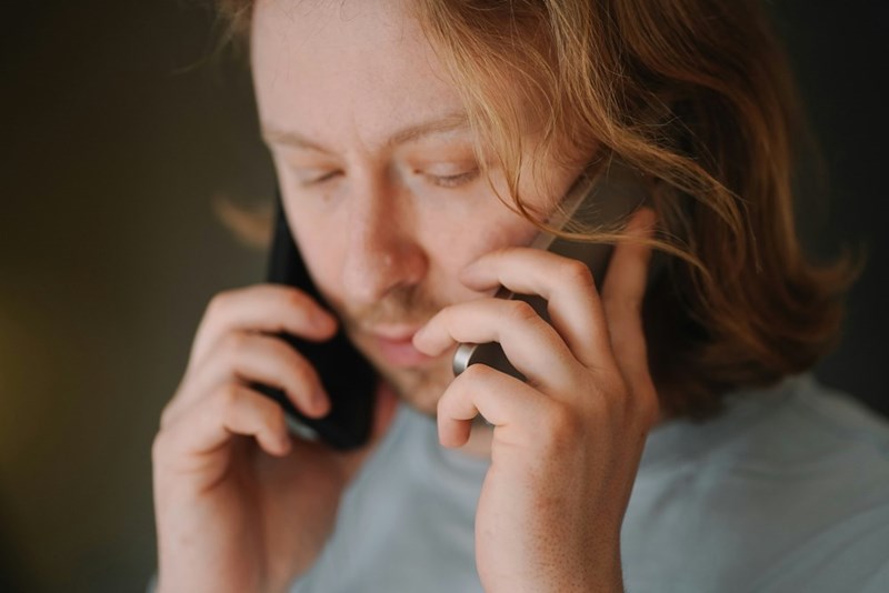 Man talks on two phones simultaneously, displayed by a model.