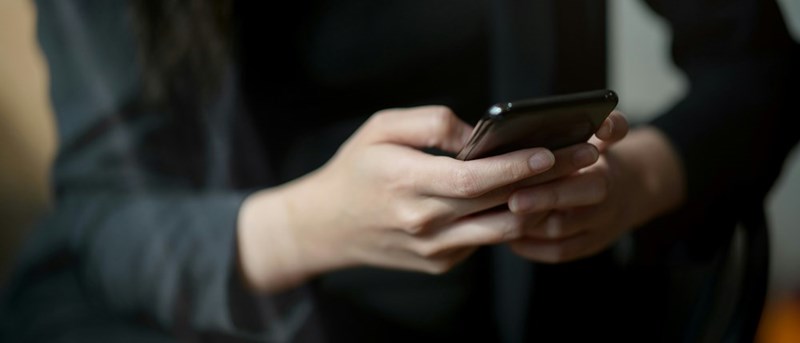 A close-up view of businessperson texting on a smartphone while sitting in an office room