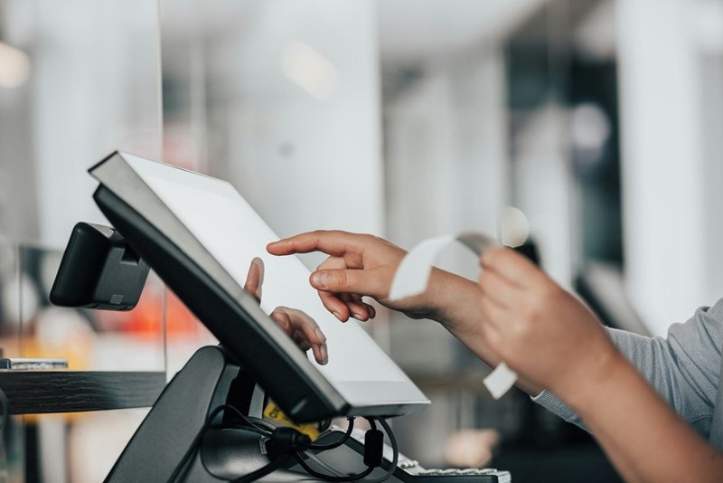 Representation of a worker operating a cash register with a touch screen.
