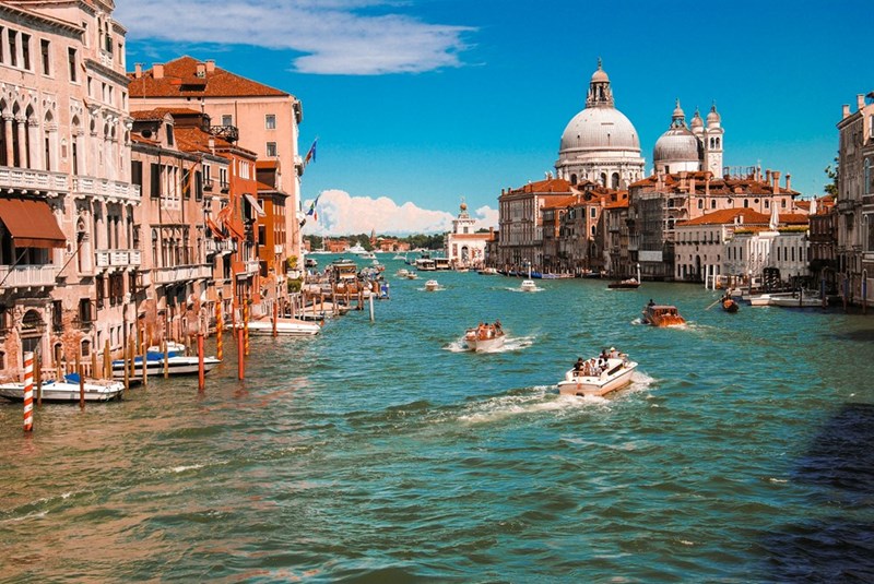 Bustling Italian waterway with surrounding city buildings, as shown in a representative photo.