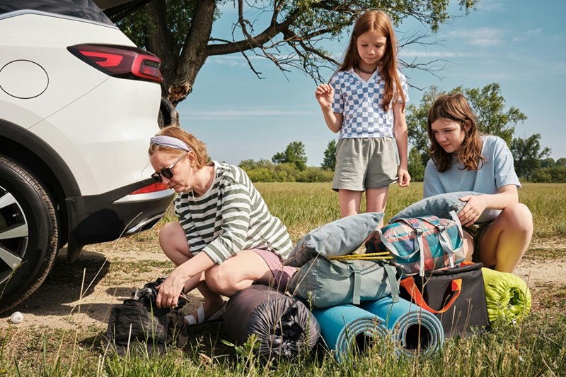 MIL and 2 young family members go through their belongings during a car trip, as depicted by models.
