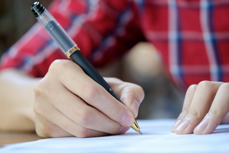 Nicely manicured hands write with a pen on paper (model)