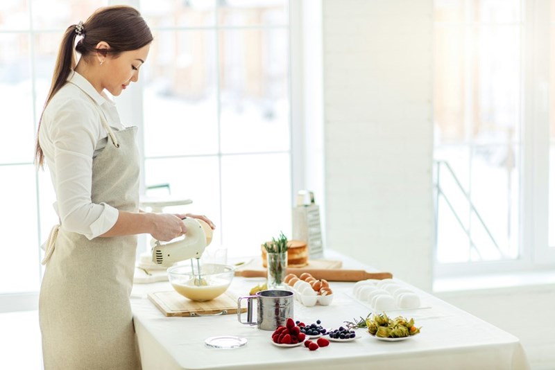 Woman smiles while preparing a fresh homemade breakfast for her firefighter husband, as a model displays.