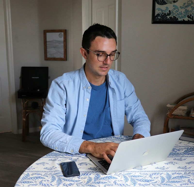 An image representing a remote employee typing on his laptop as he works from home.