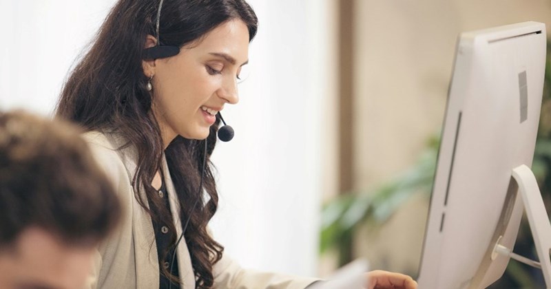 A subject (not the actual person represented in this reporting) works at a customer service support center with a headset on.