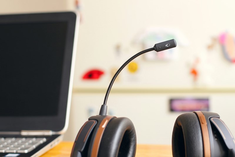 A black and brown headset near a laptop computer.