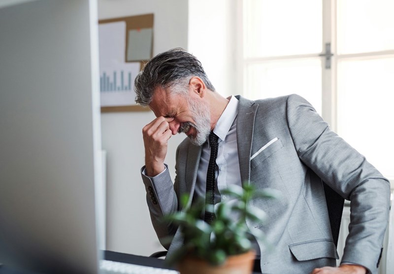 A representation of a frustrated businessman reading something upsetting on his computer.