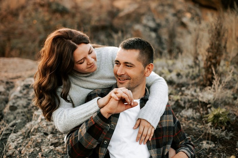 A young couple embraces outdoors, symbolizing trust, companionship, and the challenges of shared housing arrangements.