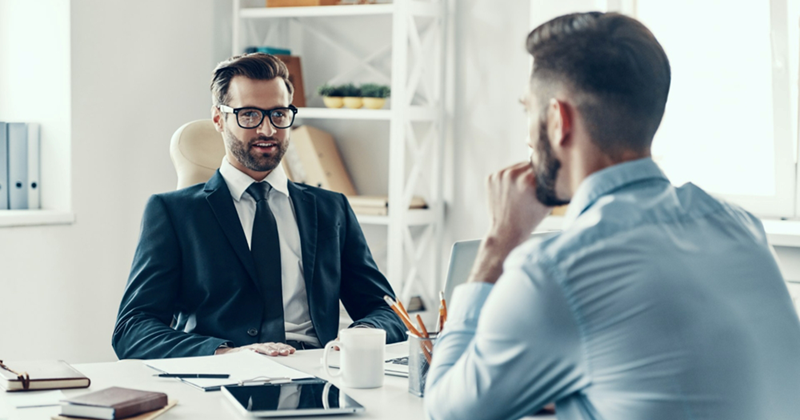 A representation of a job interviewer conducting an interview with an applicant across a desk