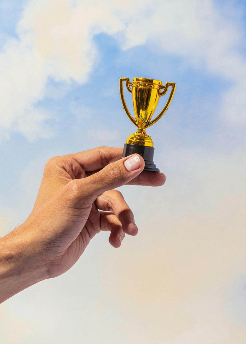 A woman holds a small participation trophy, which serves as a way of giving awards to children who didn't accomplish anything, so they feel better about themselves. 