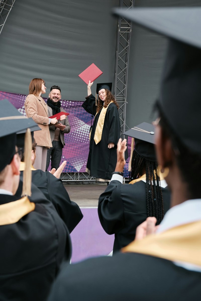 A high school student walking across the stage at graduation, accepting her diploma, regardless of whether she earned it or not. 