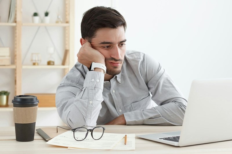 A representation of a frustrated male employee looking at his laptop at work.
