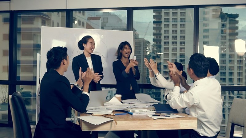 A depiction of a human resources team applauding two women presiding the meeting.