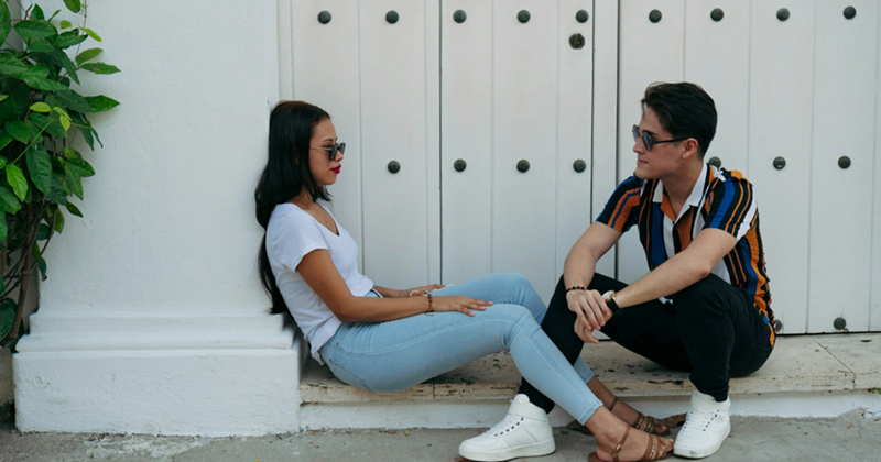 Models representing a male and female couple sitting together on a large doorstep, next to shrubbery